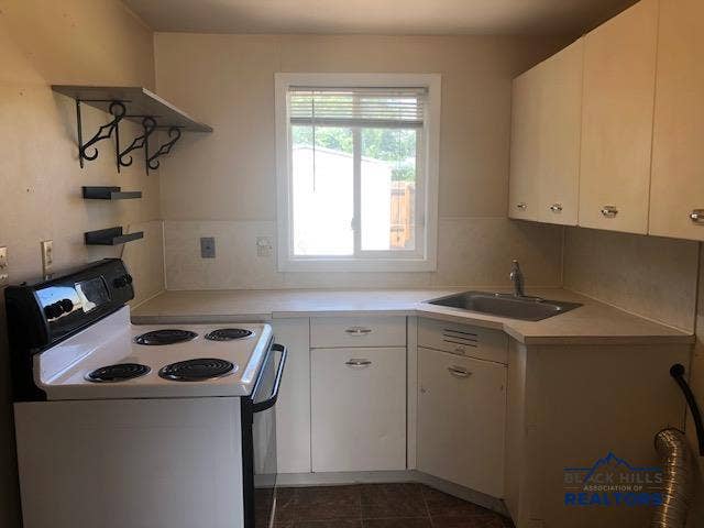 Electric range conveys; flooring is sheet vinyl, the cabinets are steel
