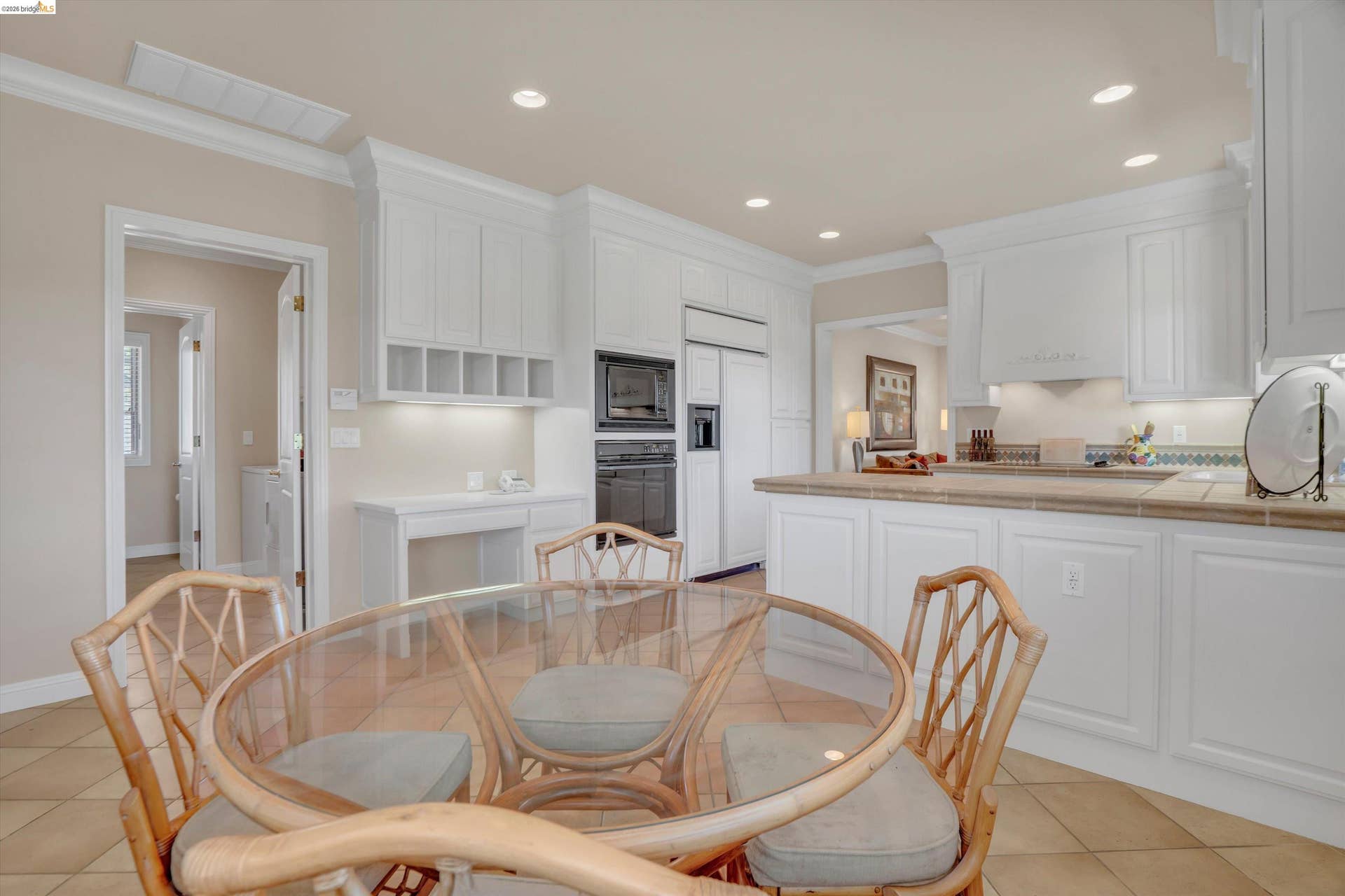 Spacious kitchen featuring white cabinetry, integrated appliances, recessed lighting, and a tiled countertop and backsplash