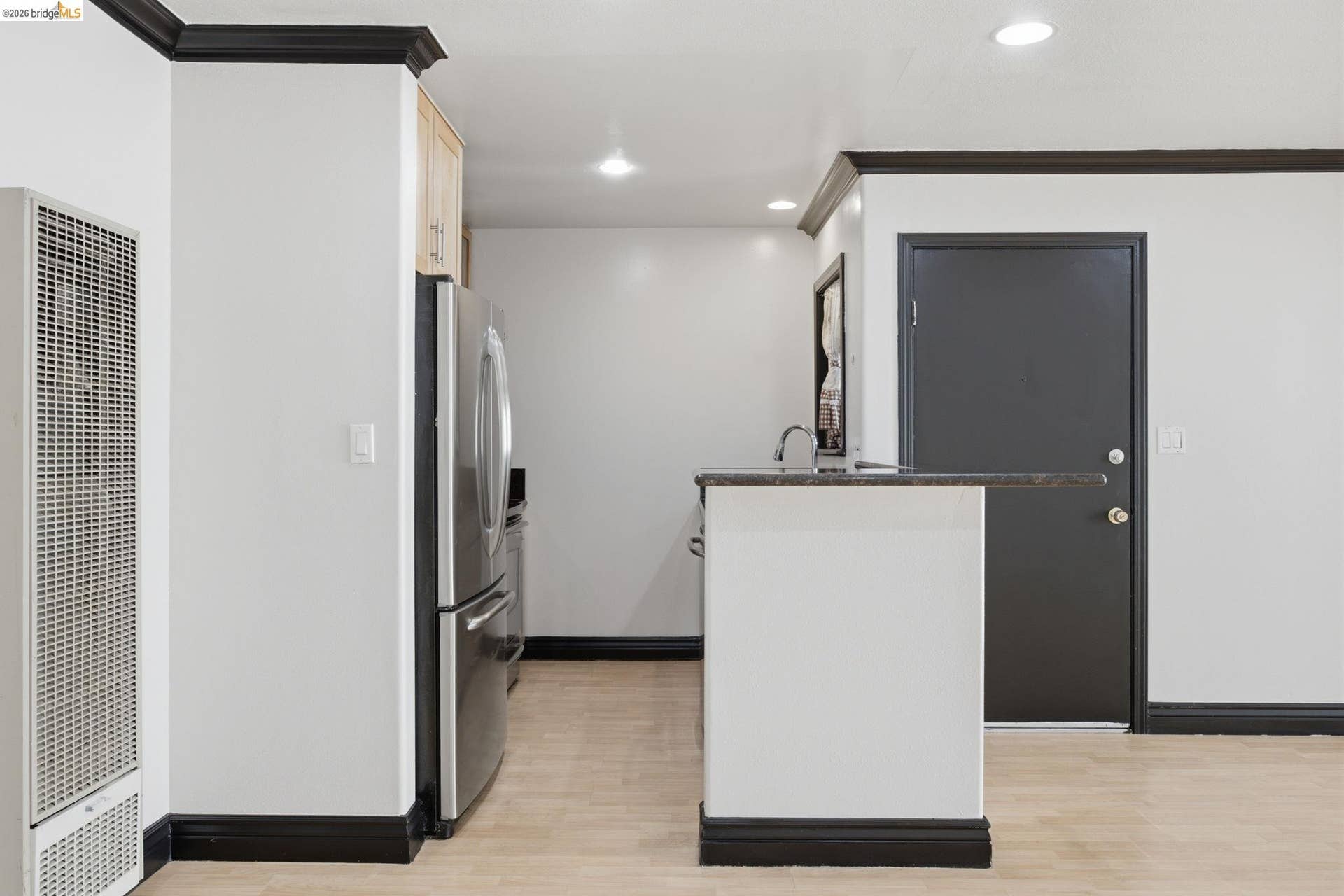 Kitchen area featuring wood-finish flooring, stainless steel refrigerator, and recessed lighting