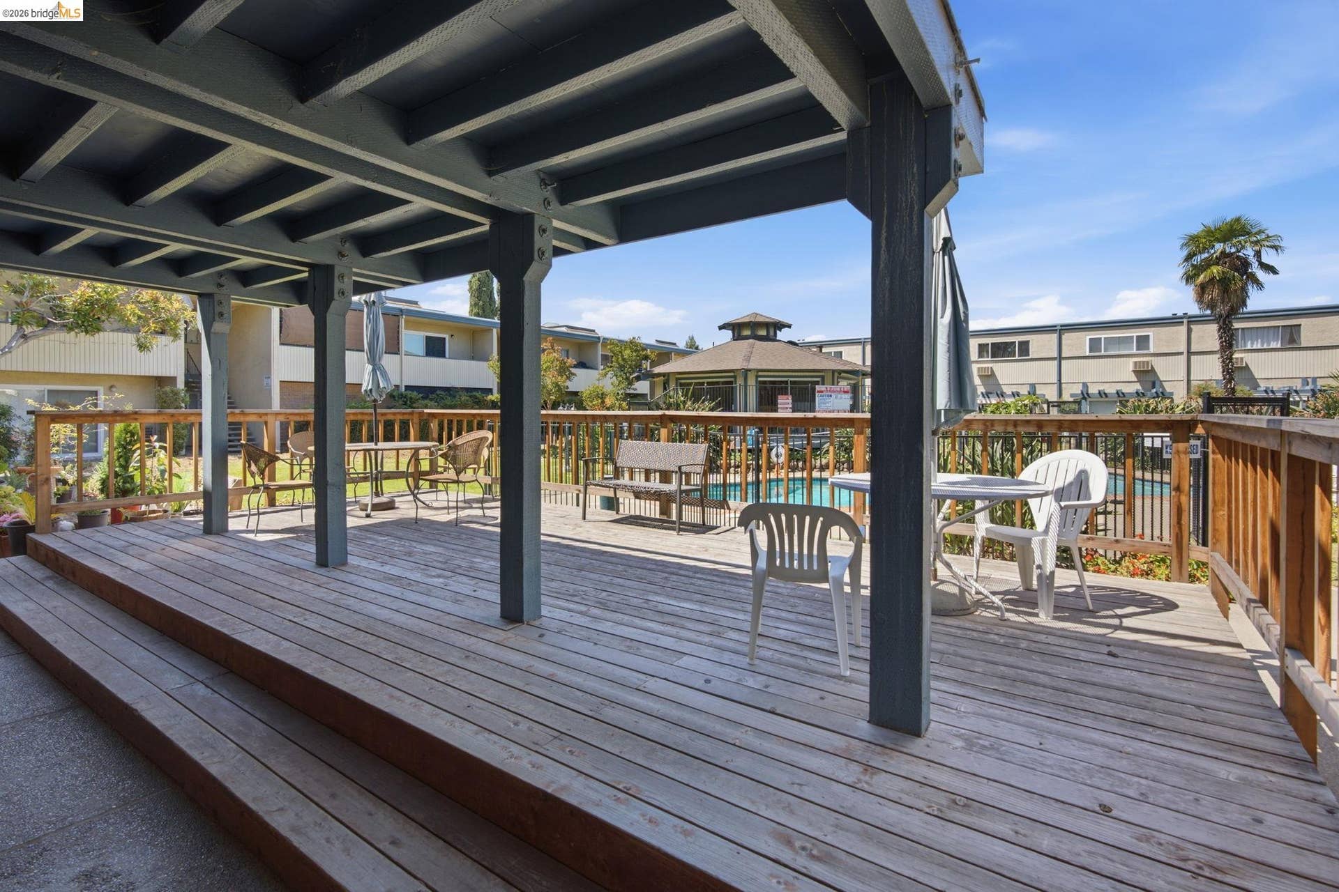 Covered outdoor deck featuring a wooden railing and steps