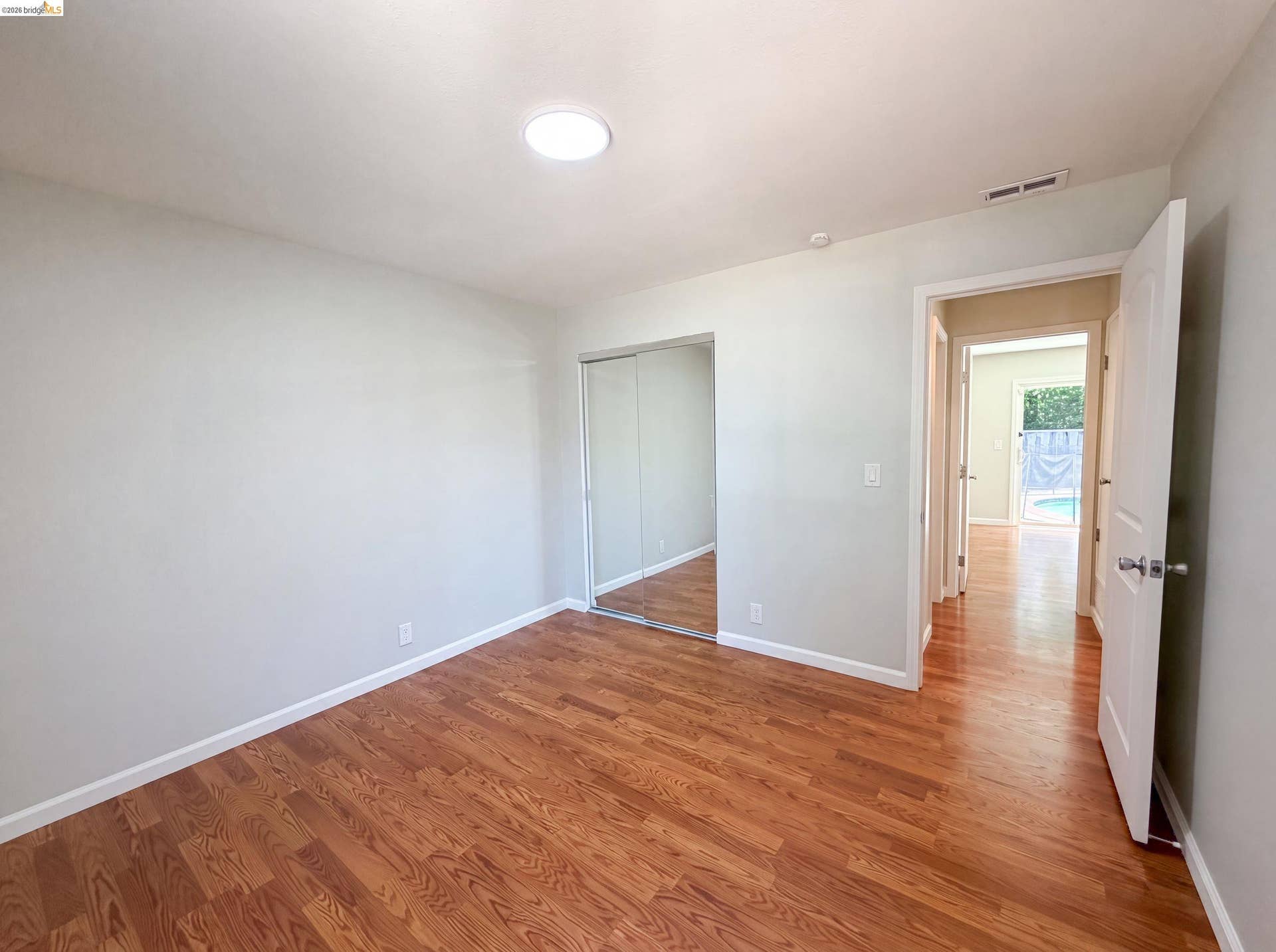 Room featuring wood-finish flooring, white baseboards, and light gray painted walls