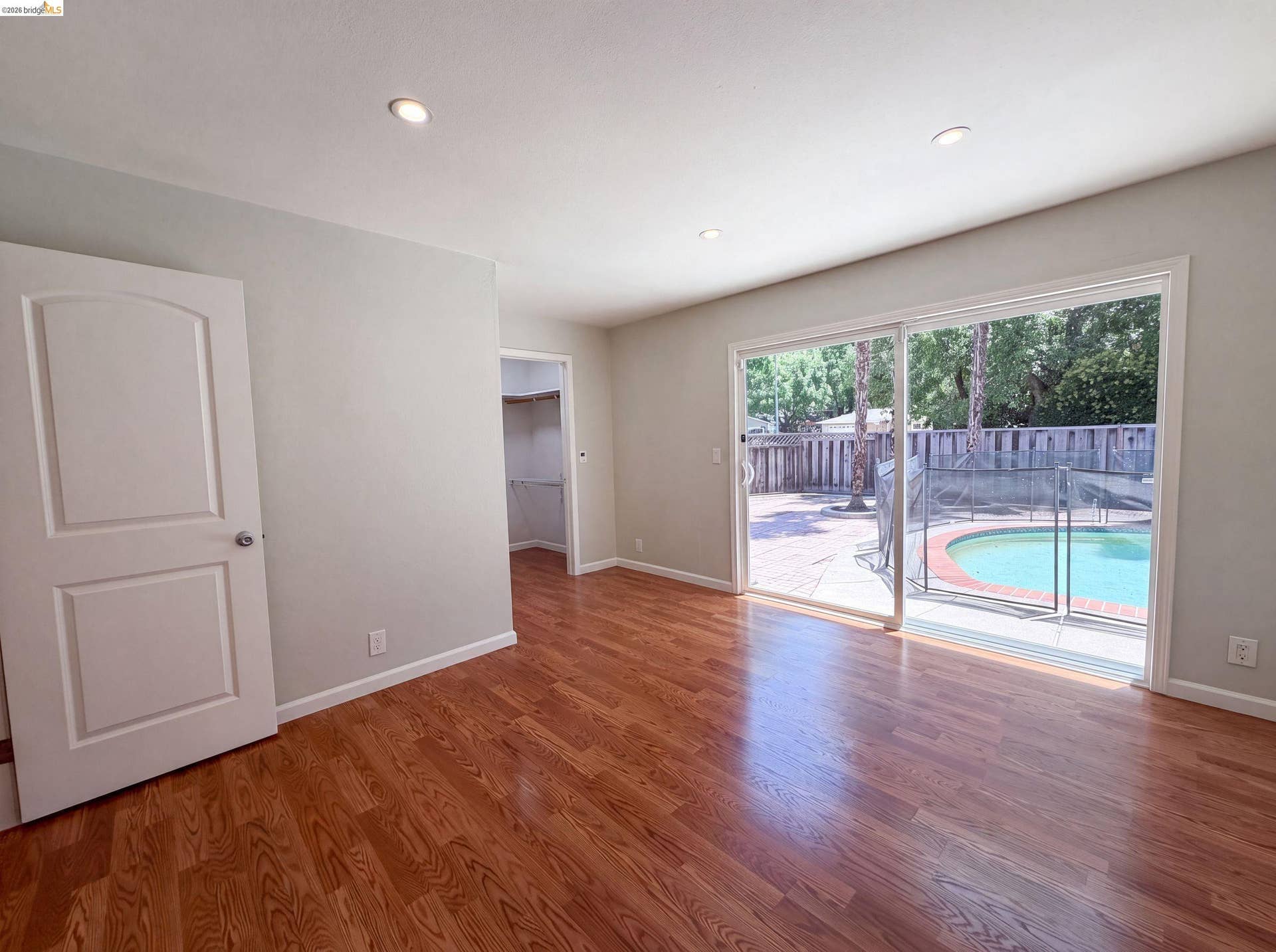 Wood-finish flooring throughout, featuring a sliding glass door providing direct access to the outdoor patio and swimming pool