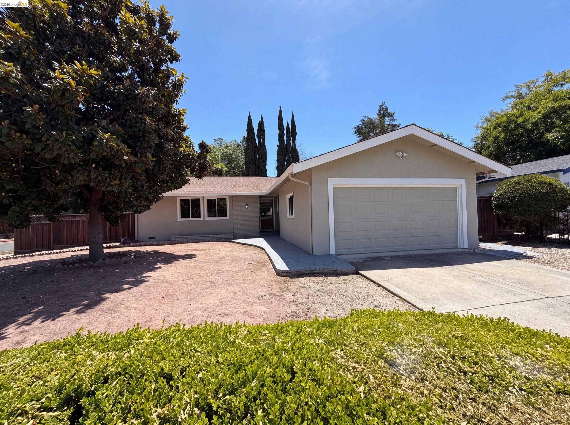 Single-story residence featuring a neutral-toned stucco exterior, a two-car garage with a panel door, and a concrete driveway