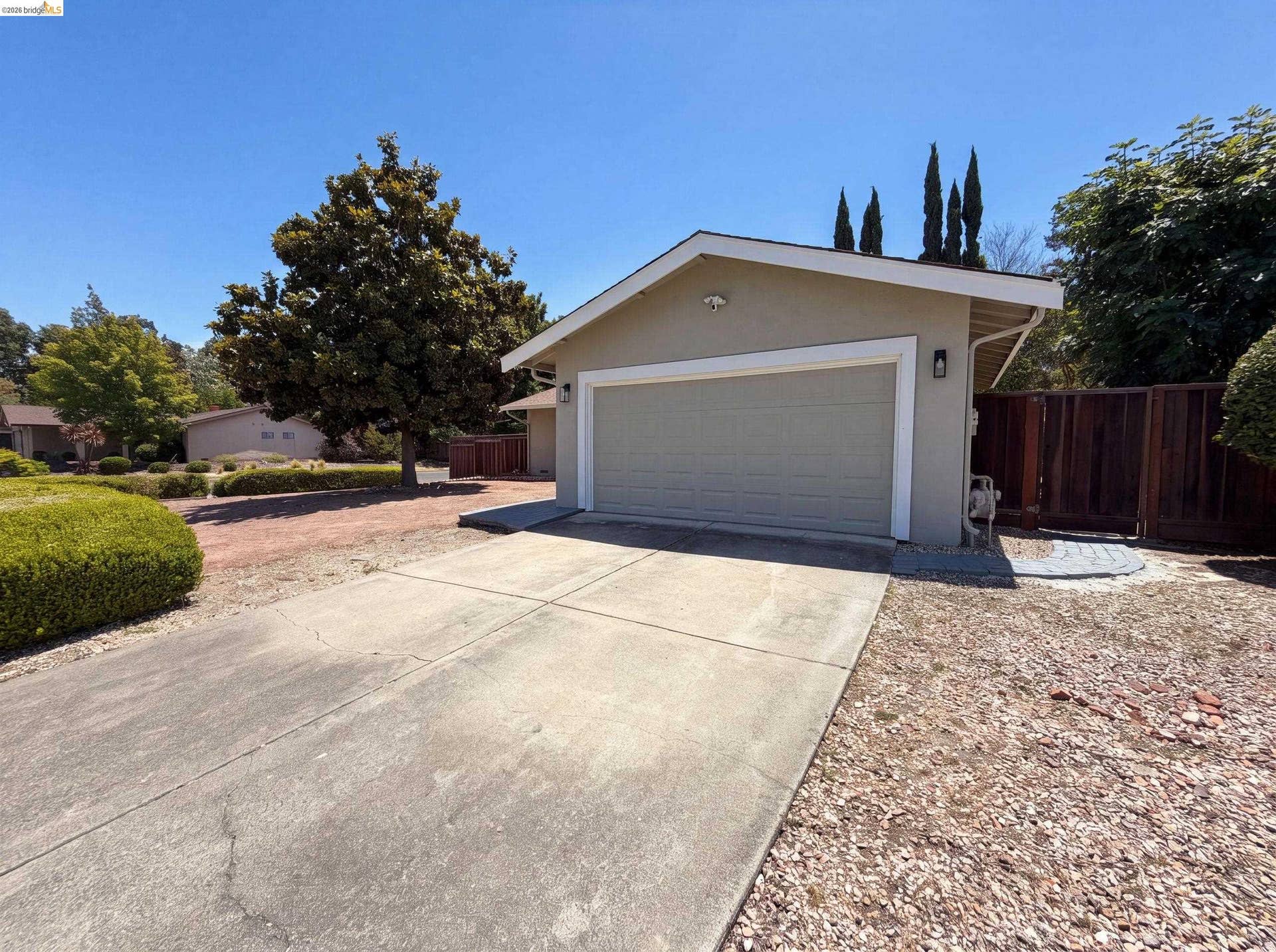 Attached garage with stucco exterior, a paved driveway, and established front yard landscaping