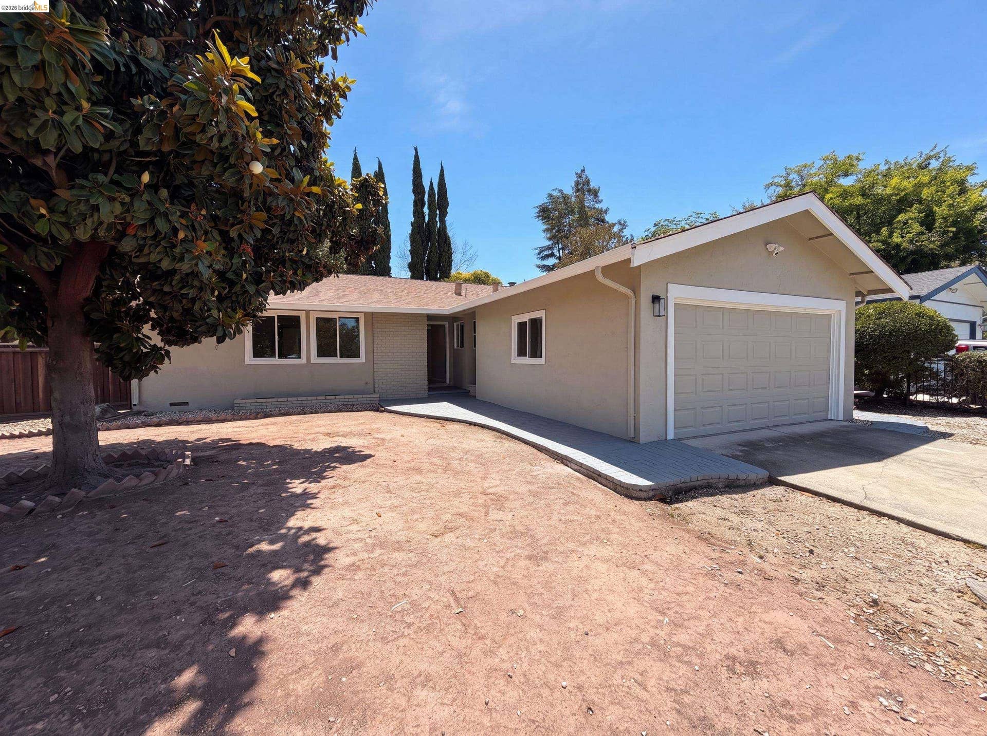 Single-story stucco exterior with an attached garage, a brown shingle roof, and white window frames