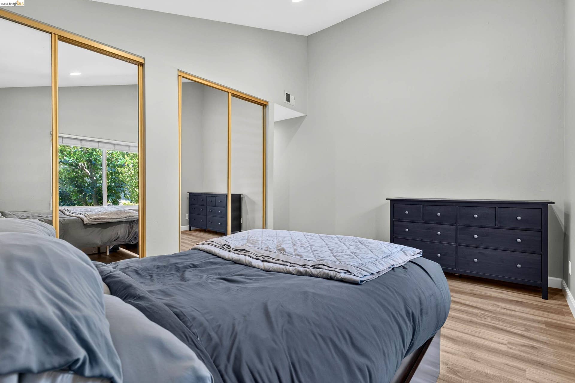 Spacious room featuring vaulted ceilings, light gray walls, and wood-finish flooring