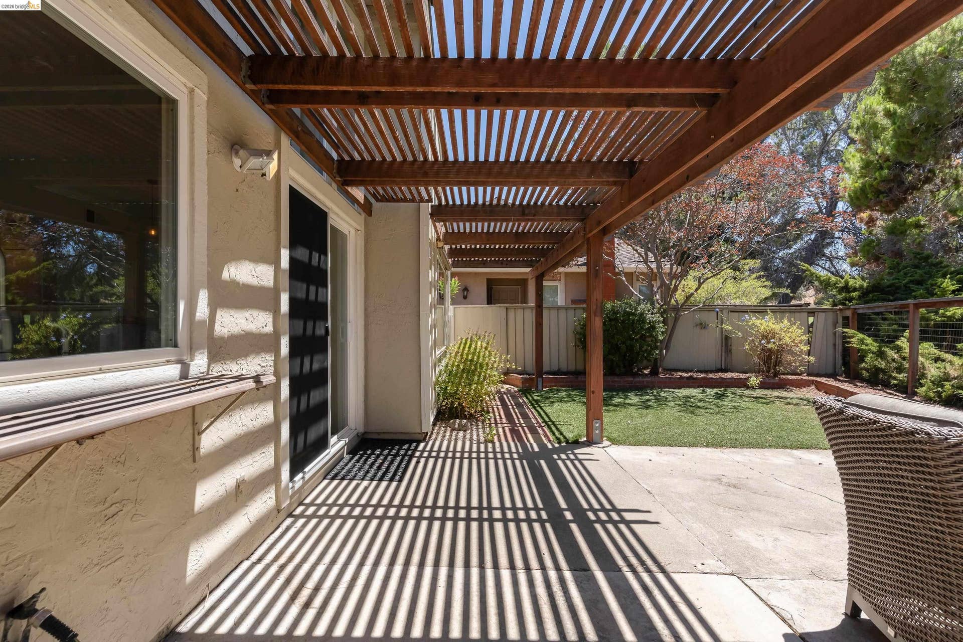 Spacious patio featuring a wood pergola, concrete slab, and an adjacent lawn area