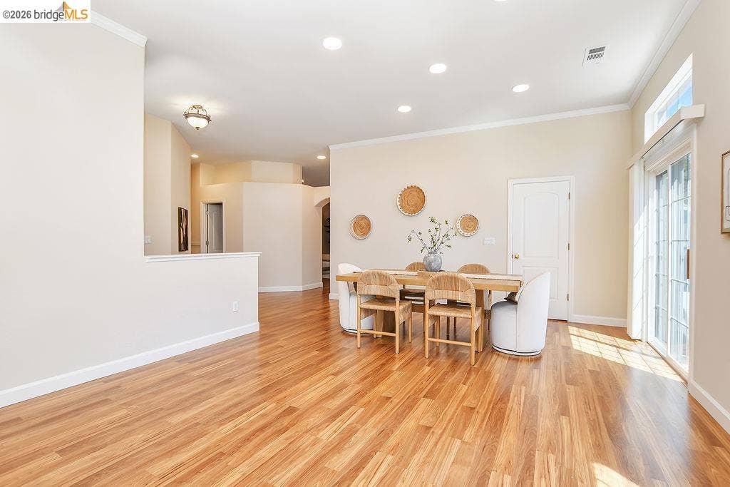 Recessed lighting, crown molding, wood-finish flooring, half-wall partition, and sliding glass door