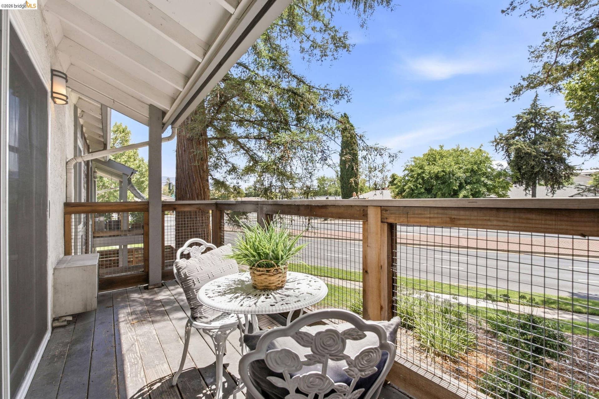 Exterior deck featuring wood-finish decking, a wooden railing with wire infill, and a white overhead patio cover