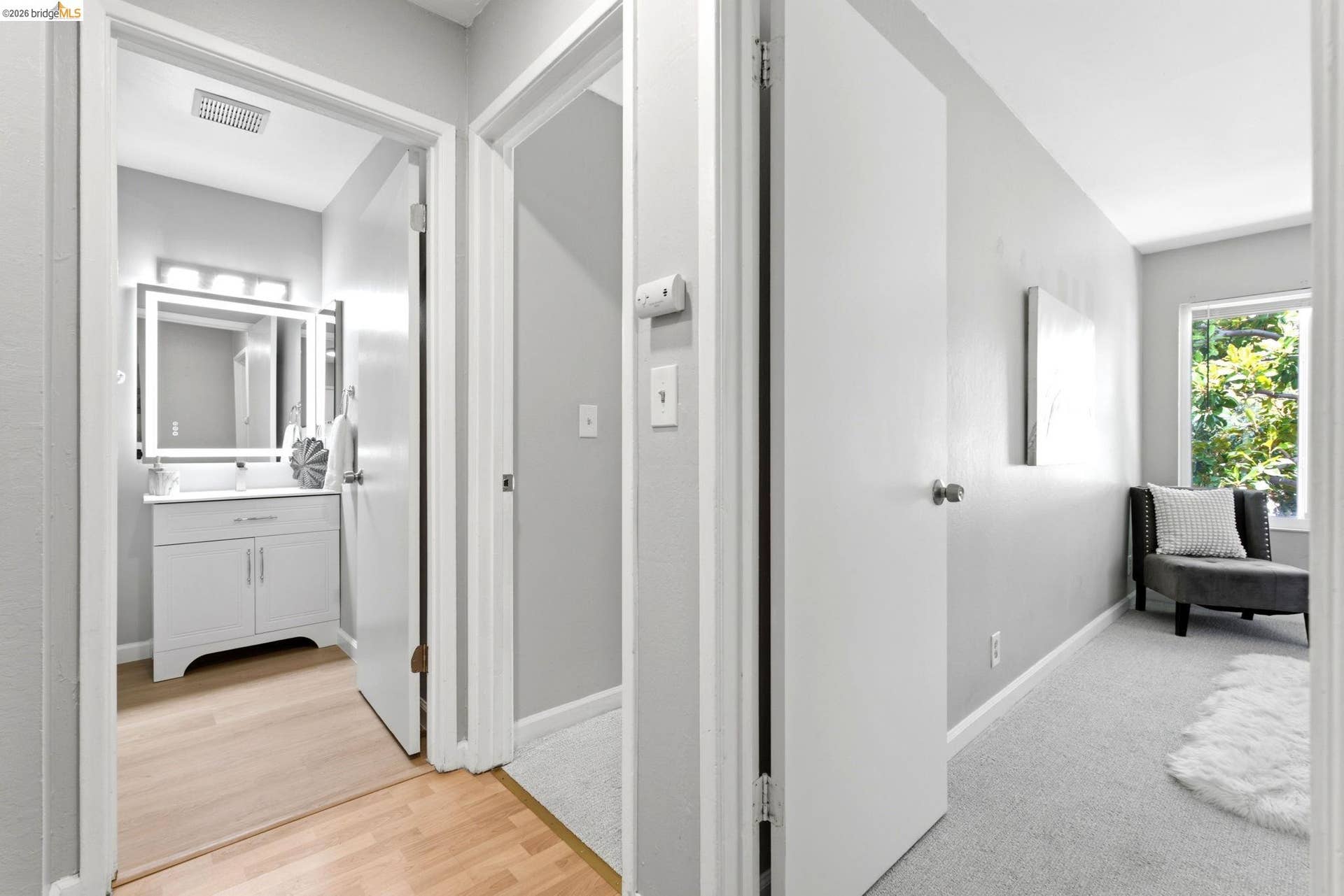 Bathroom vanity featuring a vessel sink, an illuminated mirror, and a three-light fixture