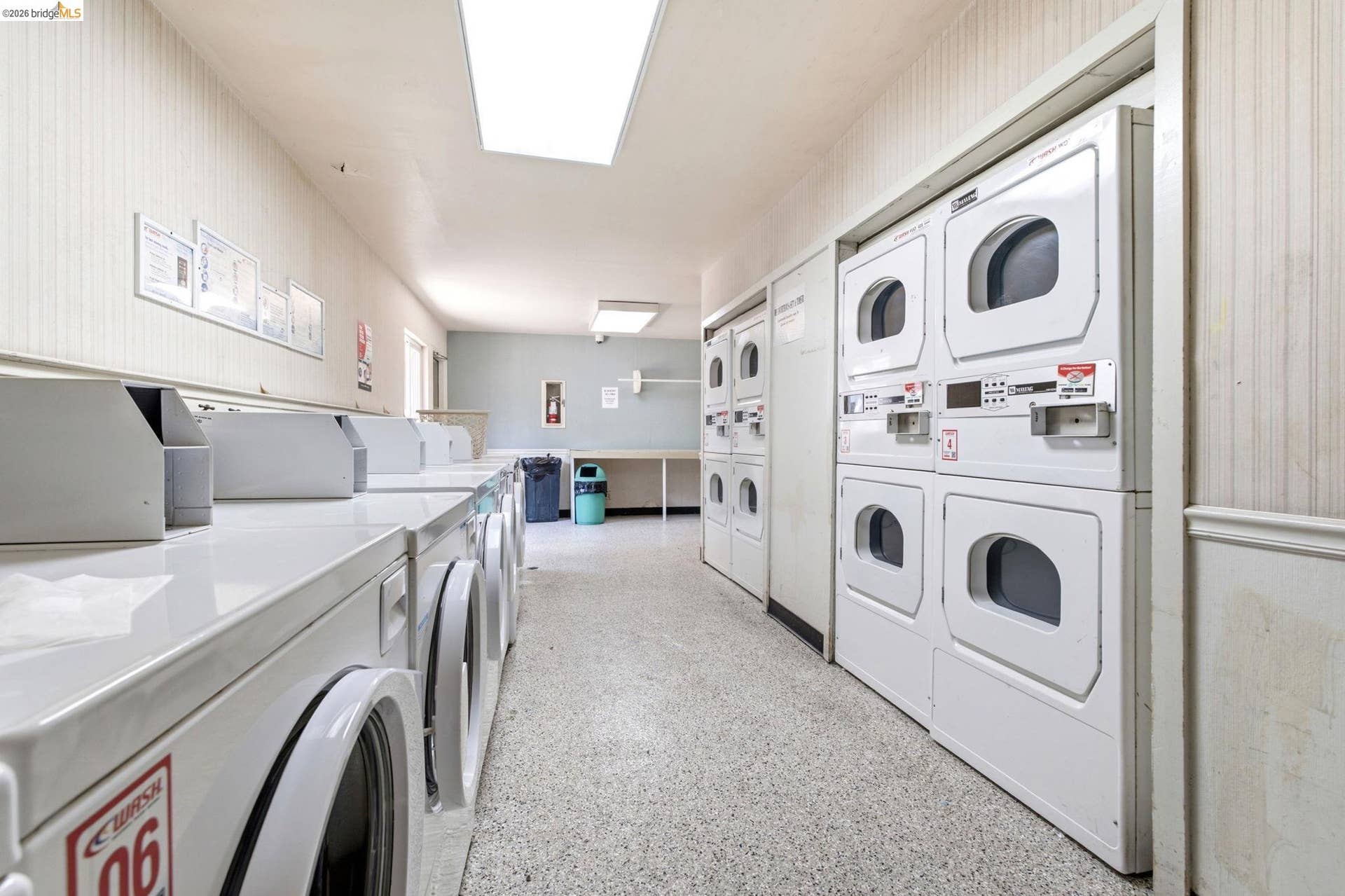 On-site laundry facility featuring multiple front-loading washing machines and stacked dryers, complemented by a light-toned flooring