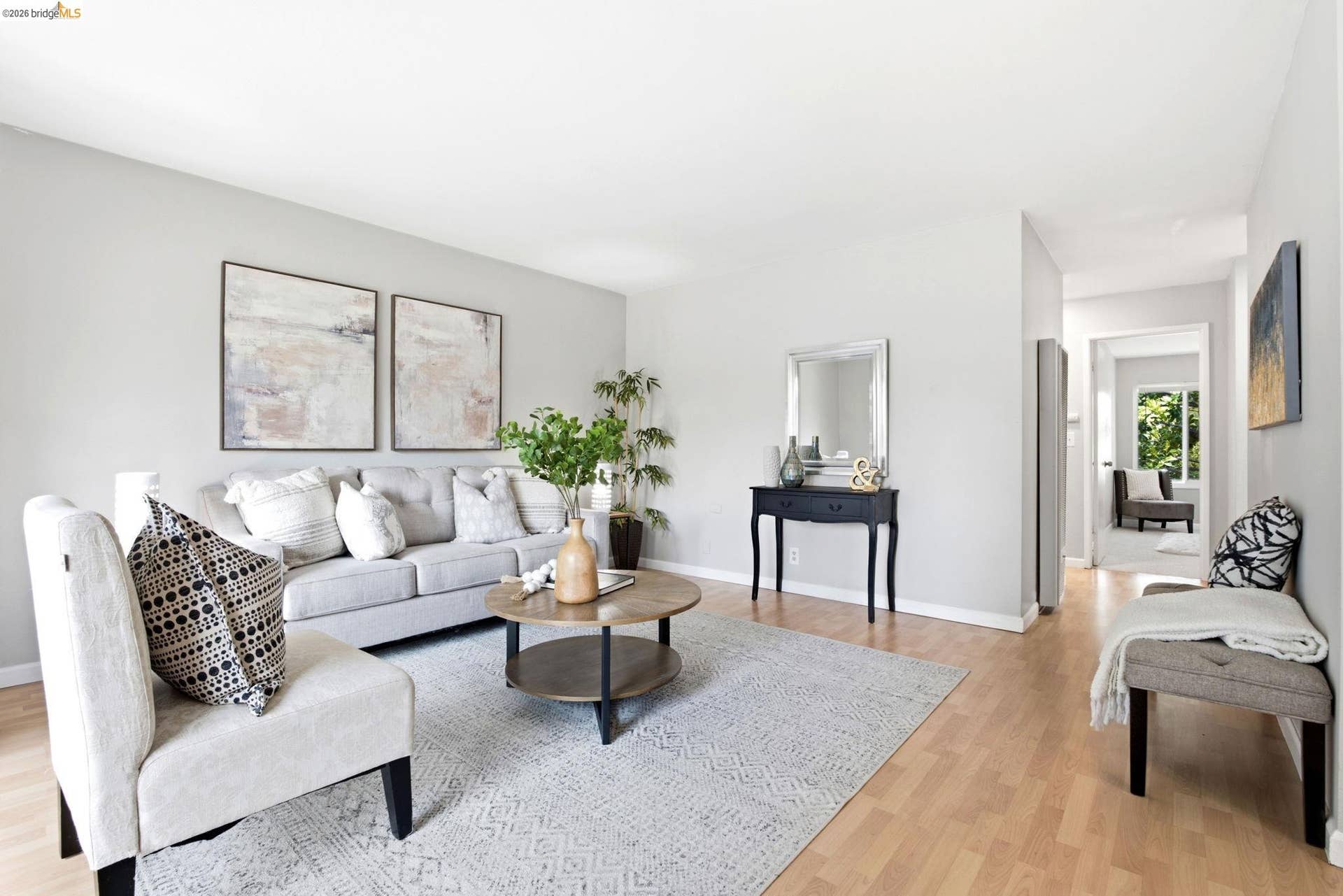 Spacious living area featuring light wood-finish flooring, light gray wall paint, and white baseboards