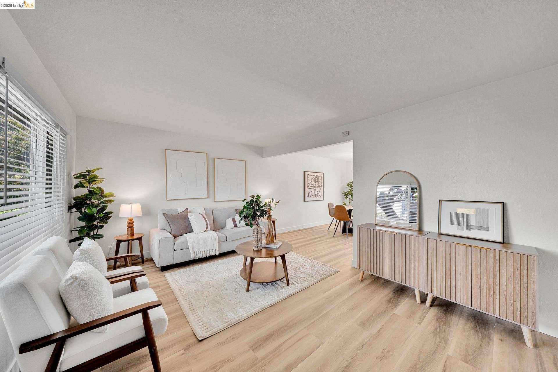 Wood-finish flooring throughout, white walls, large window with blinds, recessed lighting, and a wide entryway