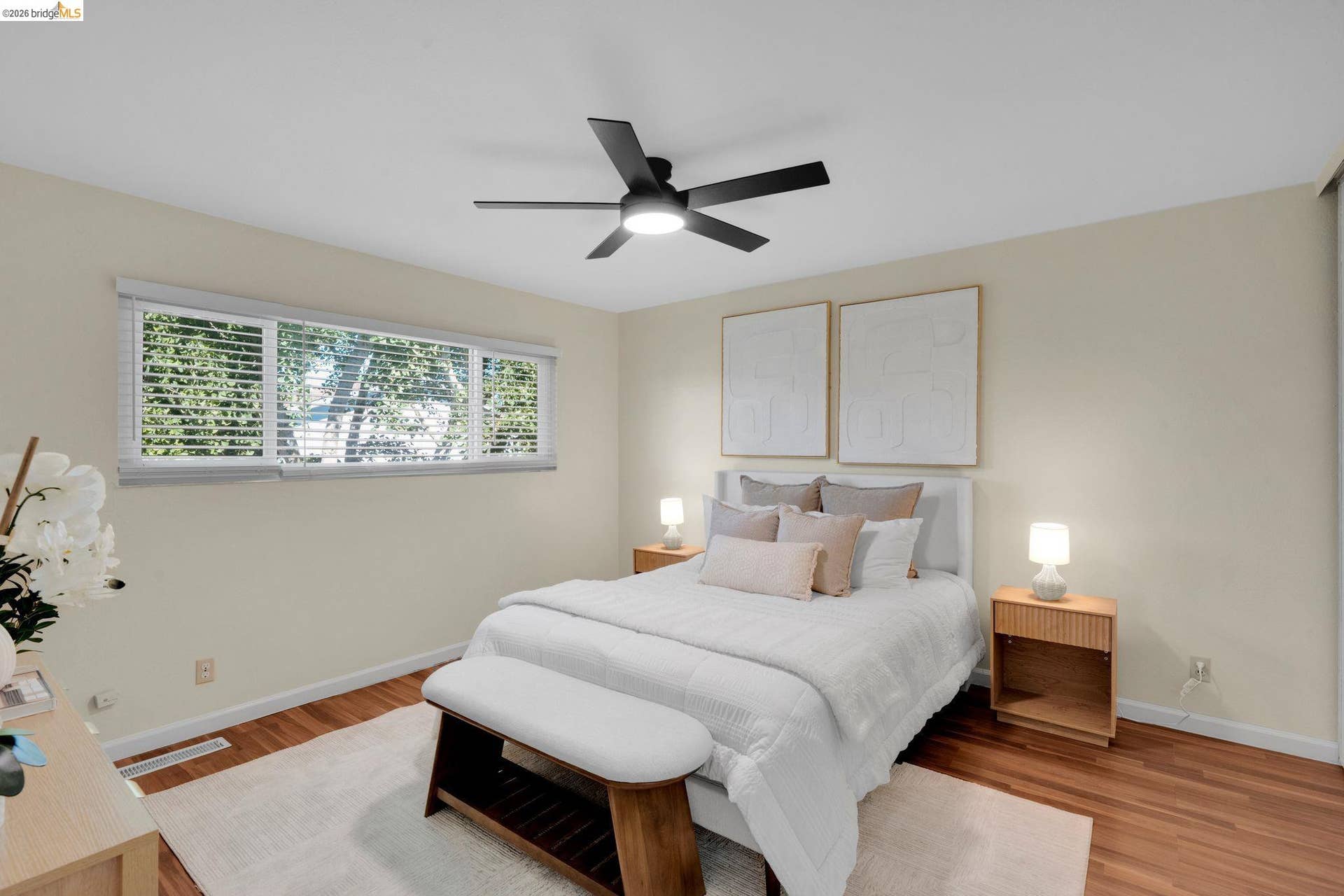 Hardwood flooring, triple window with blinds, ceiling fan, and neutral wall tones