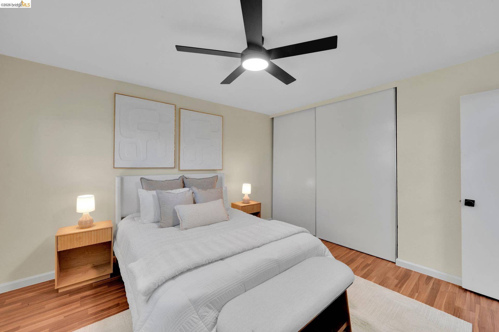 Wood-finish flooring, built-in sliding closet doors, and a ceiling fan with integrated lighting