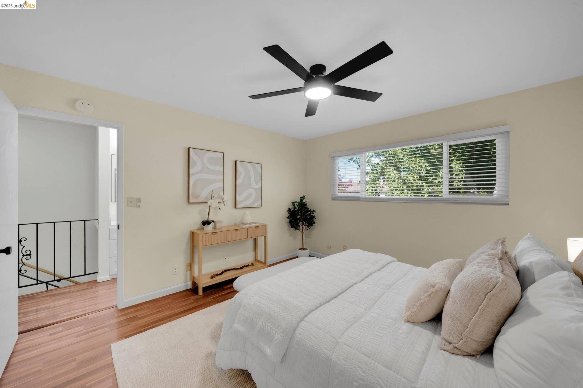 Hardwood-finish flooring, black ceiling fan with integrated lighting, horizontal window blinds, and white interior trim