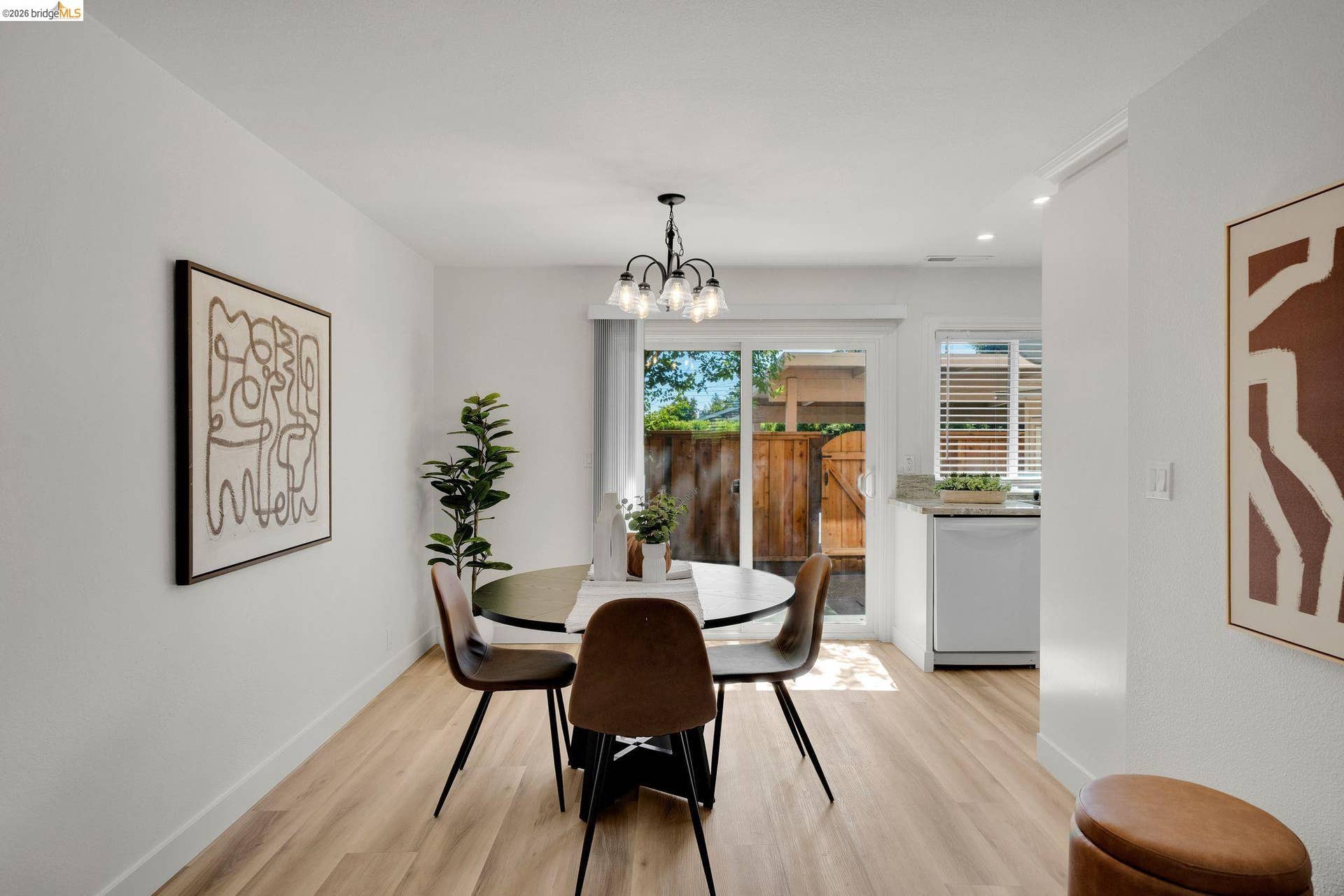 Dining area with wood-finish flooring, a contemporary chandelier, and direct access to an outdoor space via a sliding glass door