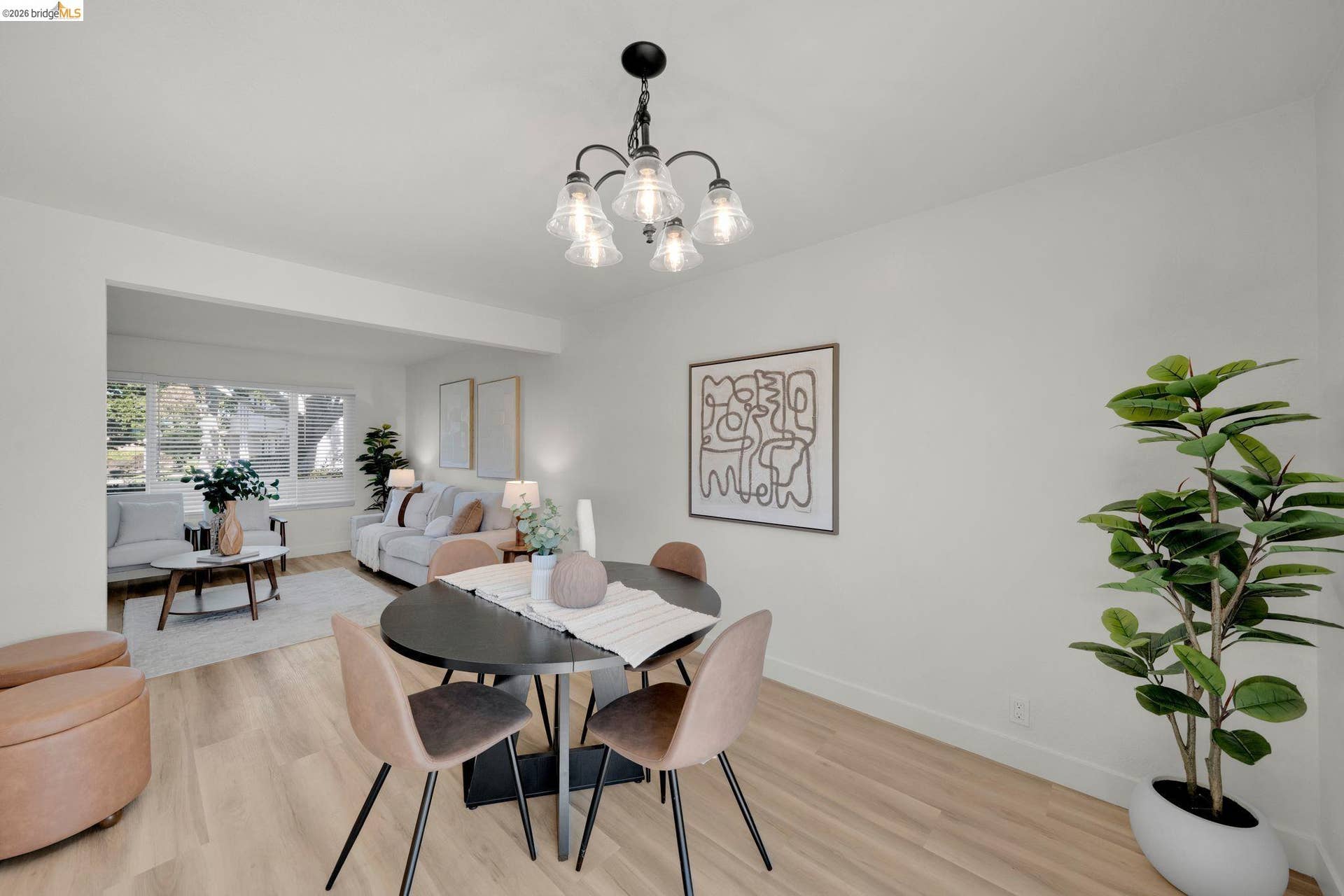 Wood-finish flooring throughout, a black five-light chandelier with clear glass shades, and a black round dining table