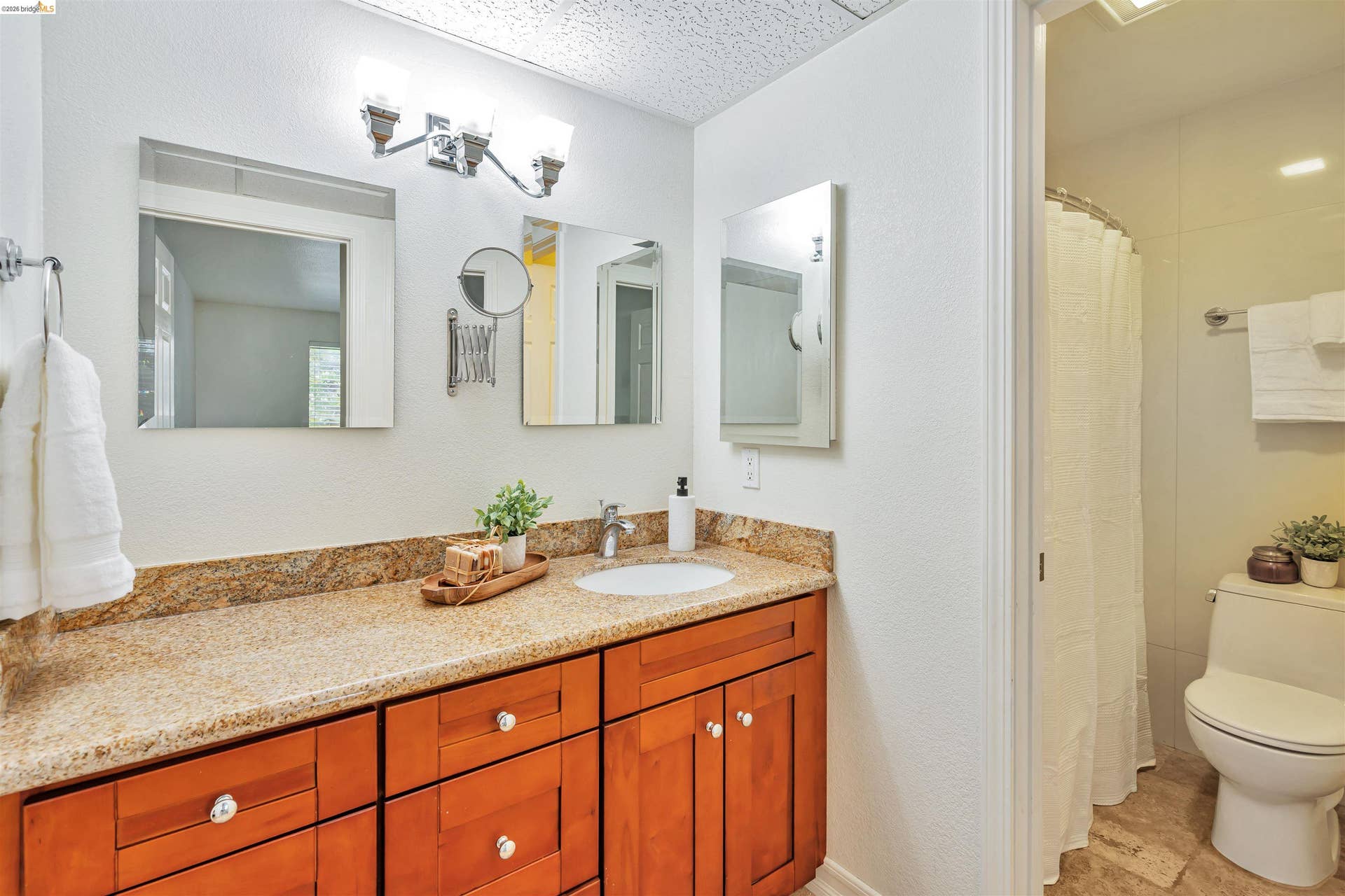 Bathroom featuring a wood-finish vanity with ample storage, a single basin sink, and a speckled countertop