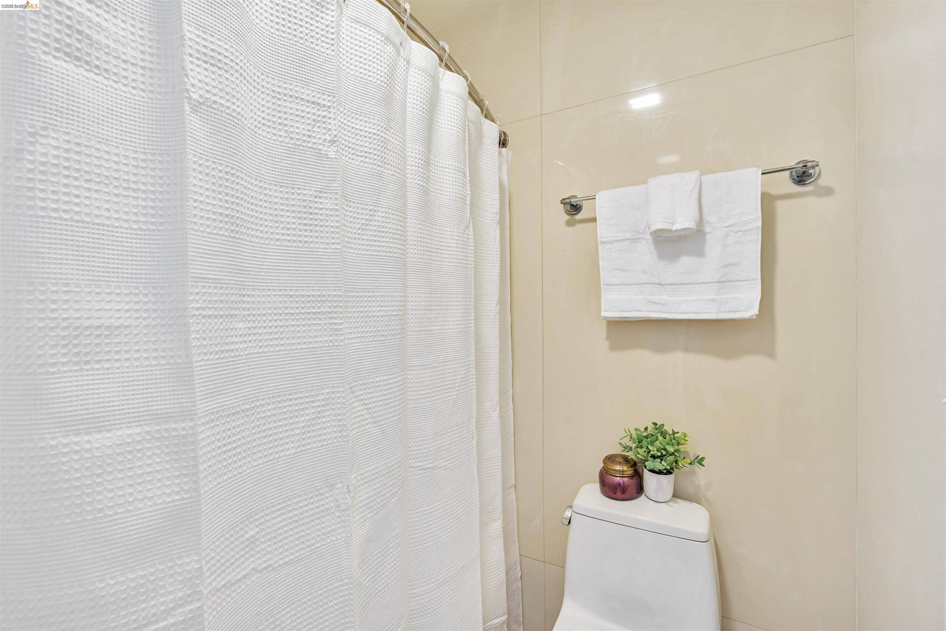 Bathroom featuring polished tile walls, a white toilet, and a chrome towel bar