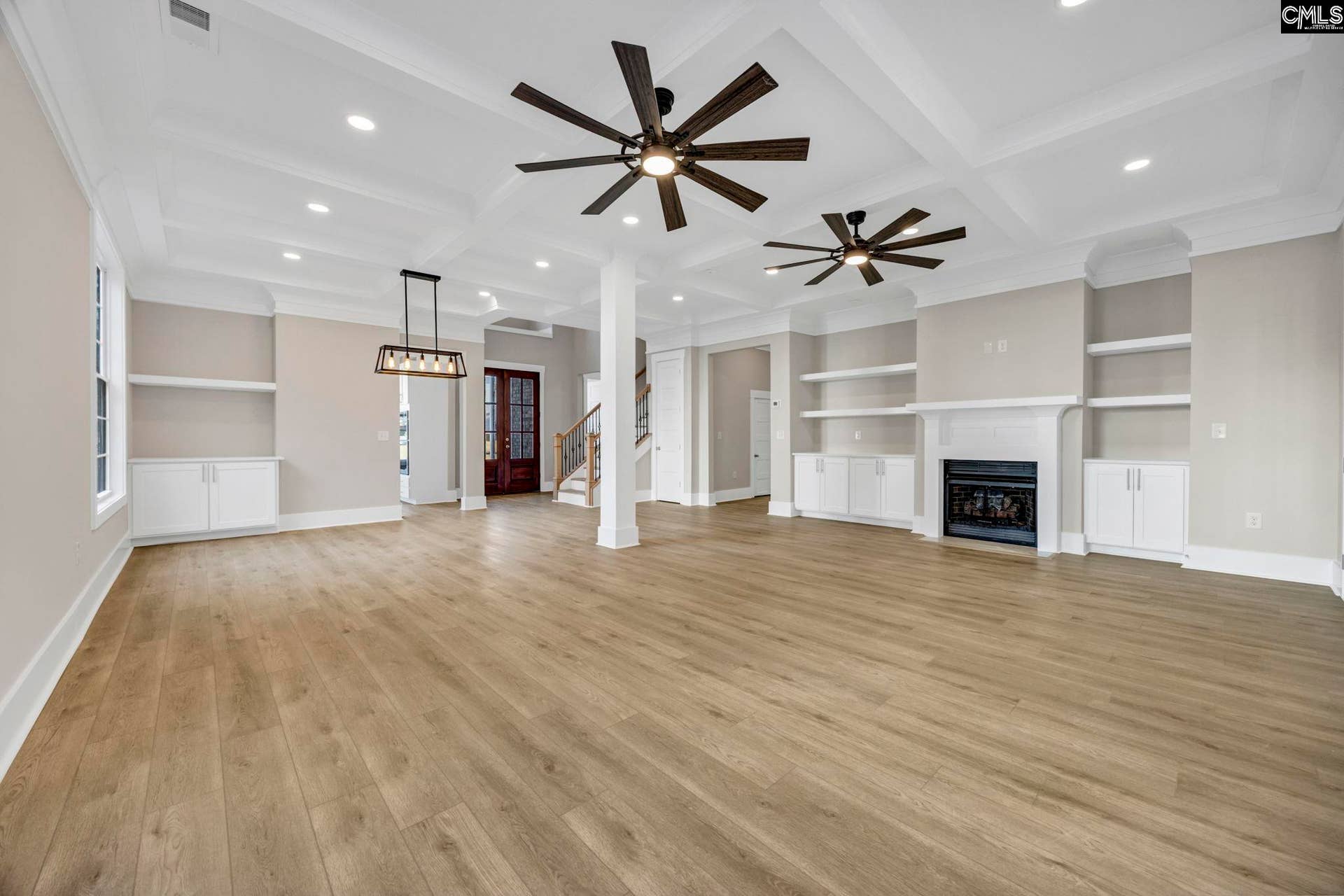 Tall coffered ceilings, recessed lighting, and dual fans add architectural detail to the living room