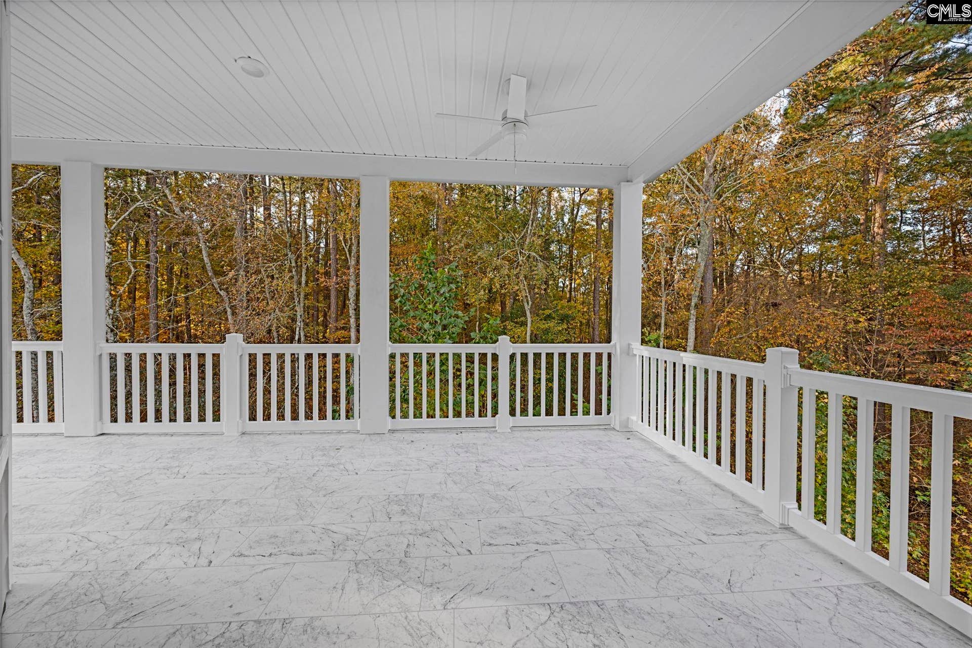 Spacious covered porch with access from two bedrooms overlooks the peaceful wooded backdrop.