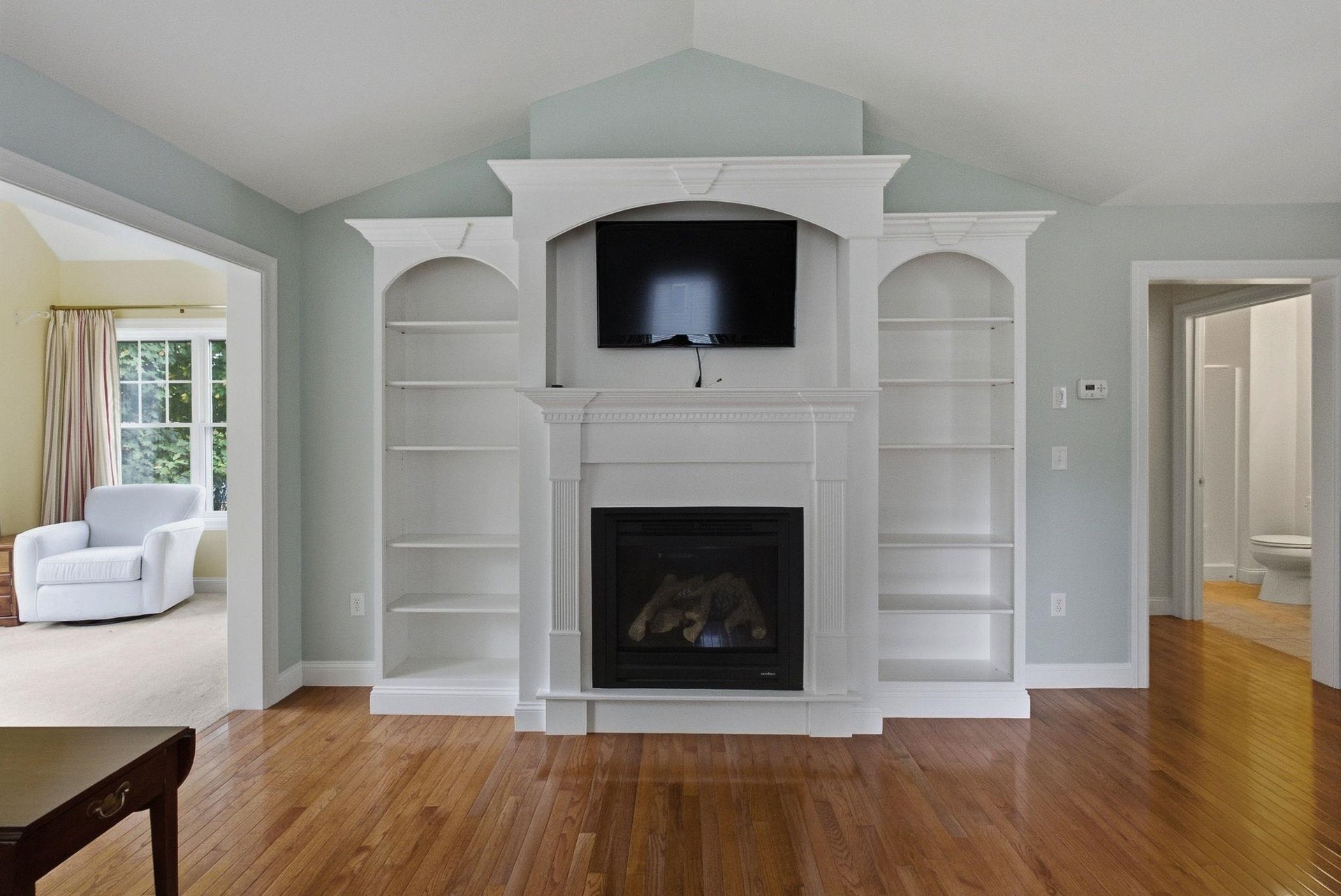 Living room has custom built in book shelves surrounding and a gas fireplace